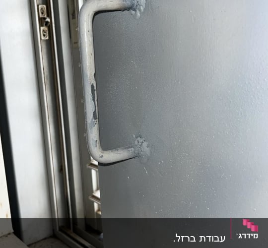 ידית מתכת על דלת אפורה